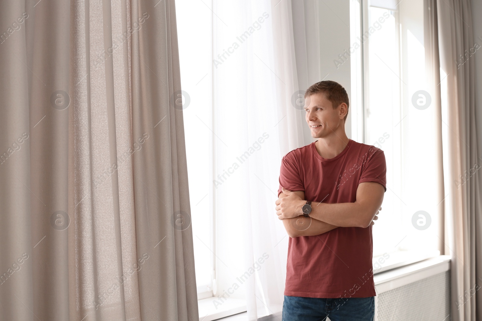 Photo of Mature man near window with open curtains at home. Space for text