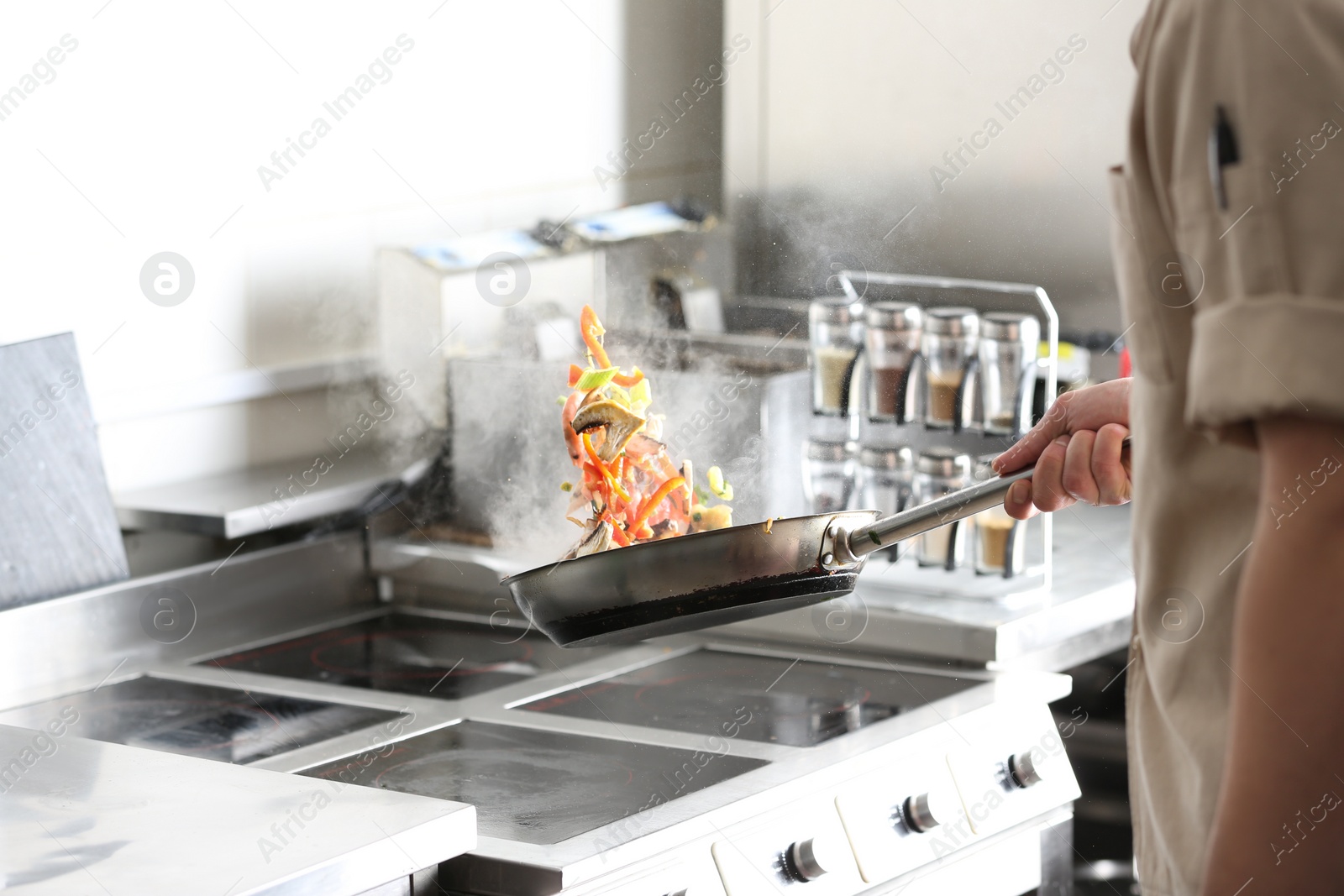 Photo of Male chef cooking tasty food on stove in restaurant 
kitchen, closeup of hand