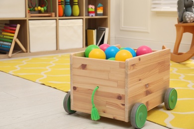 Toy car trailer with colorful balls in playroom. Interior design