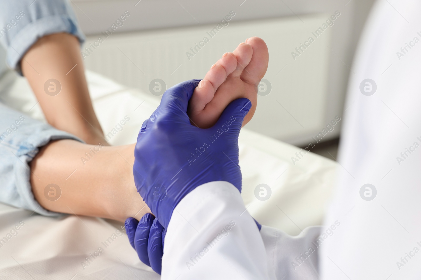 Photo of Male orthopedist examining patient's foot in hospital, closeup