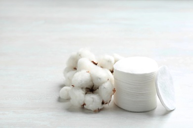 Photo of Cotton flowers and soft pads on light background, space for text