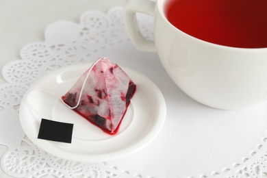 Saucer with used tea bag near cup on table