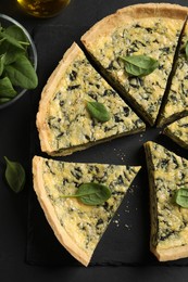 Photo of Cut delicious spinach pie on slate plate, flat lay
