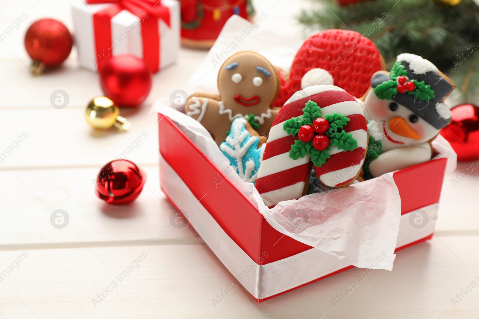 Photo of Delicious homemade Christmas cookies and festive decor on white wooden table, closeup