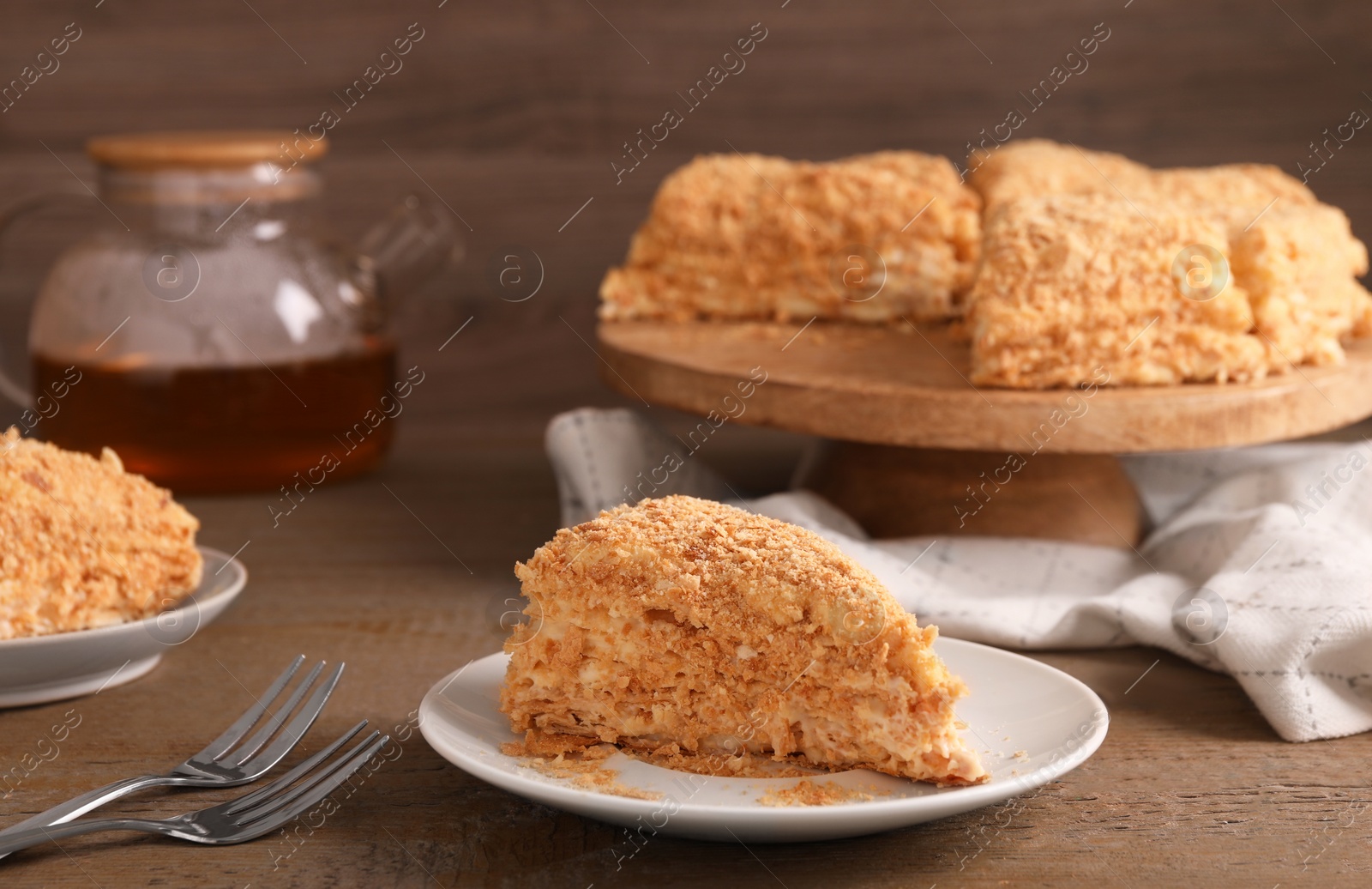 Photo of Piece of delicious Napoleon cake served on wooden table, closeup