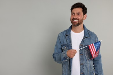 Photo of 4th of July - Independence Day of USA. Happy man with American flag on grey background, space for text