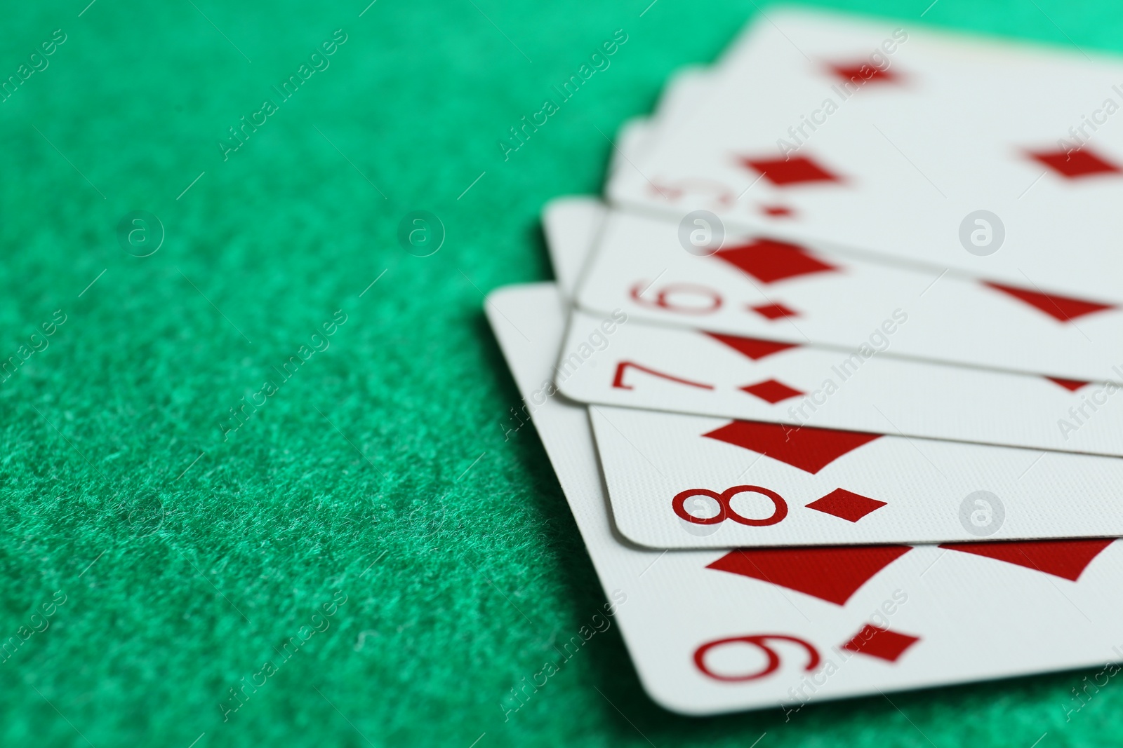 Photo of Playing cards with straight flush combination on green table, closeup. Space for text