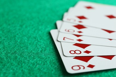 Photo of Playing cards with straight flush combination on green table, closeup. Space for text