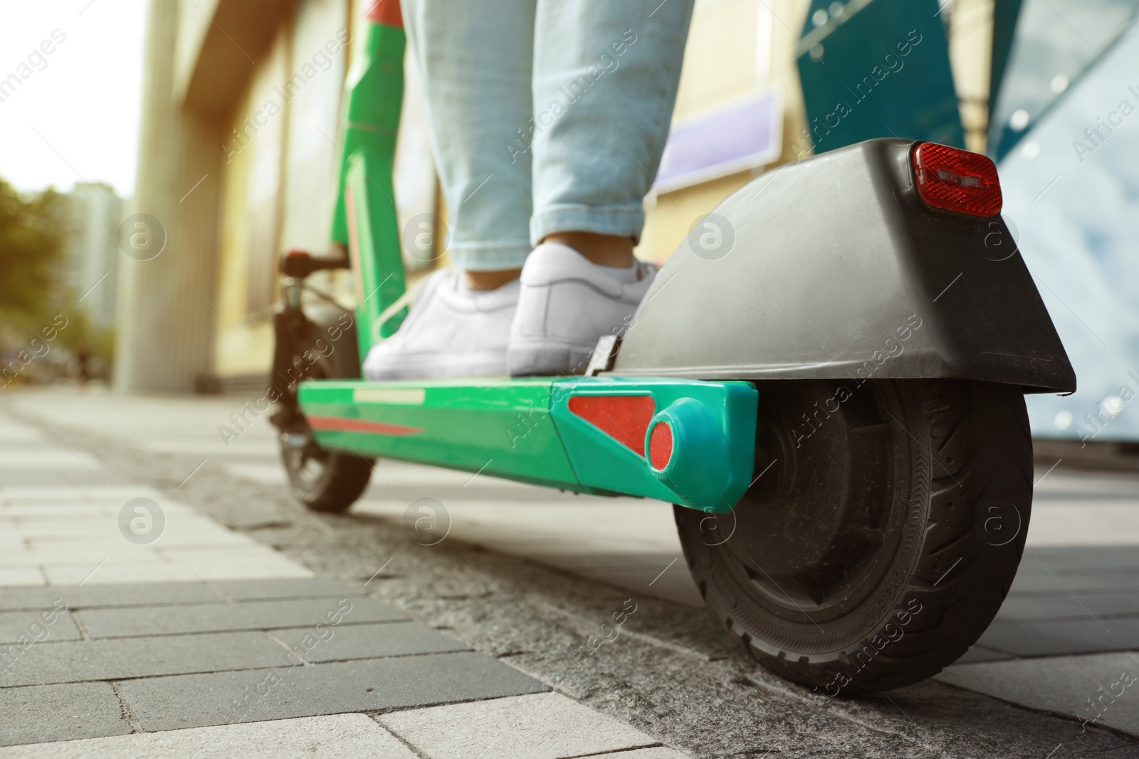 Photo of Man riding modern electric kick scooter on city street, closeup