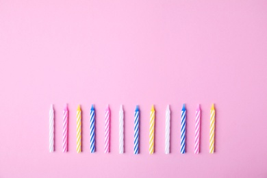 Photo of Colorful striped birthday candles on pink background, flat lay. Space for text