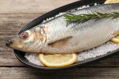 Photo of Plate with salted herring, rosemary and lemon on wooden table, closeup
