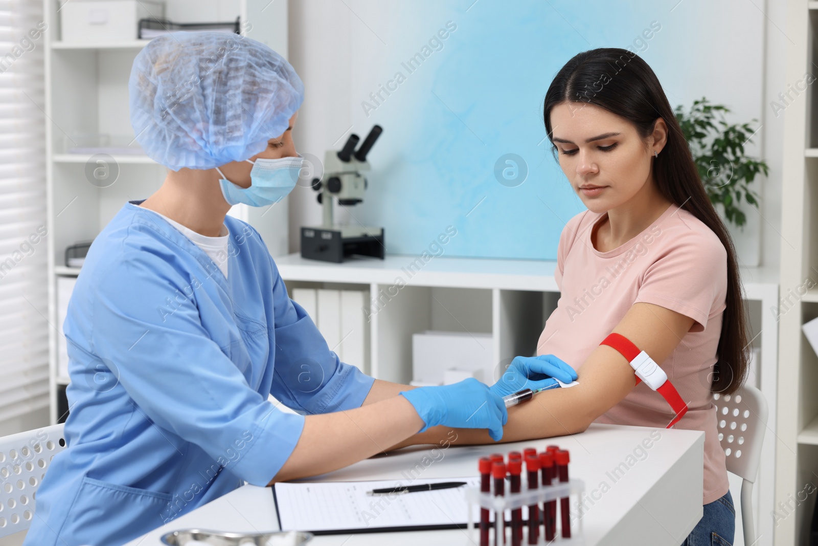 Photo of Laboratory testing. Doctor taking blood sample from patient at white table in hospital