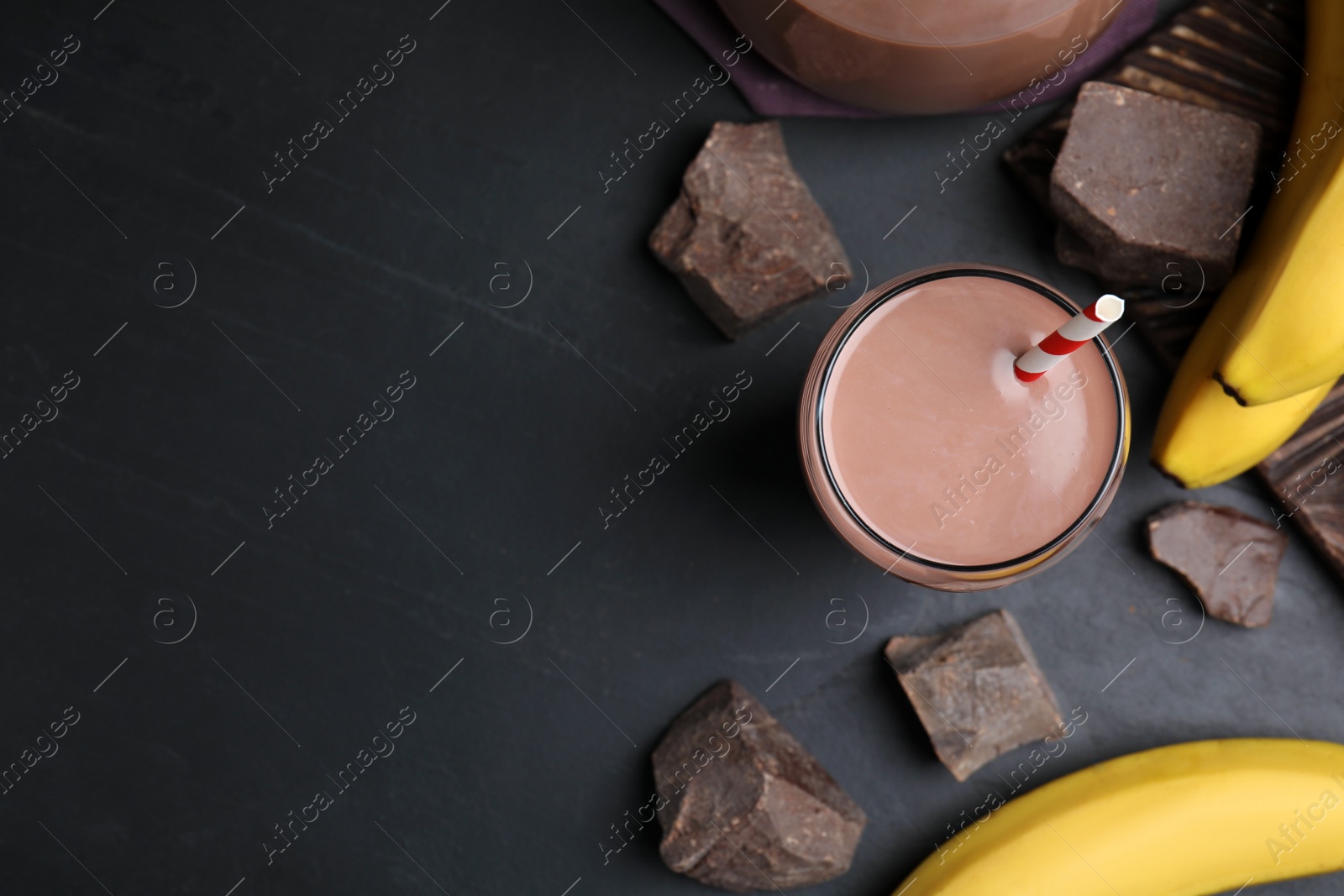 Photo of Fresh yummy chocolate milk on black table, flat lay. Space for text