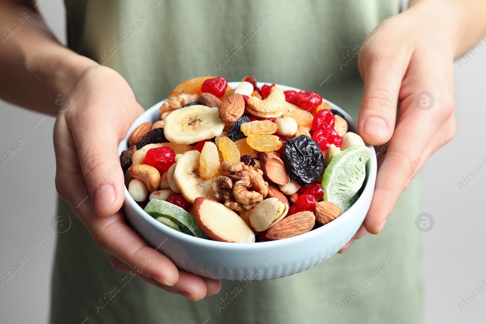 Photo of Young woman holding plate with different dried fruits and nuts, closeup