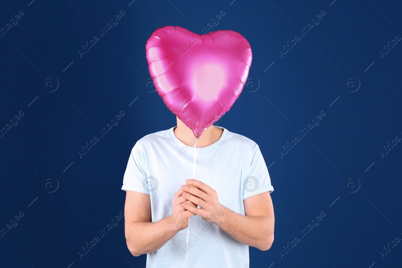 Photo of Young man with heart shaped balloon on color background