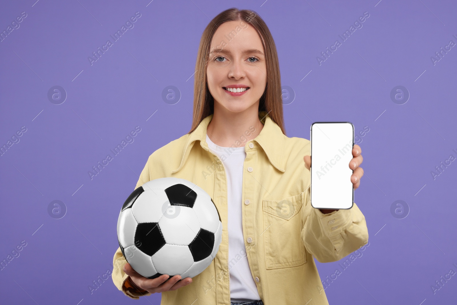Photo of Happy sports fan with ball and smartphone on purple background