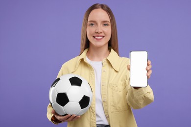 Happy sports fan with ball and smartphone on purple background