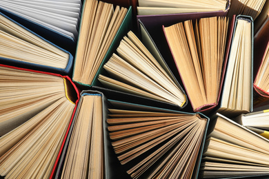 Photo of Many different hardcover books on dark background, top view