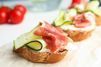 Delicious bruschettas with prosciutto on table, closeup