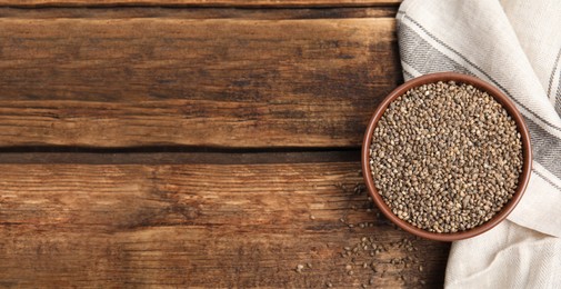 Photo of Bowl with organic hemp seeds on wooden table, flat lay. Space for text