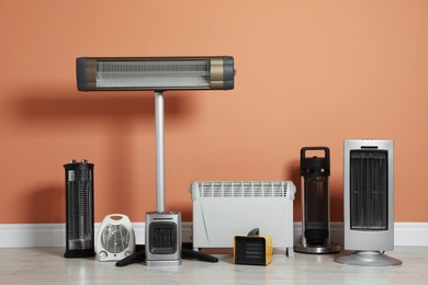 Photo of Different electric heaters near orange wall indoors