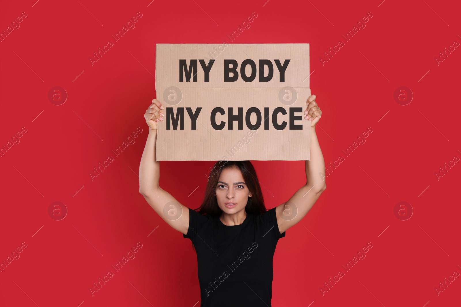 Image of Woman holding placard with phrase My Body My Choice on red background. Abortion protest