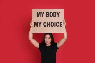 Image of Woman holding placard with phrase My Body My Choice on red background. Abortion protest