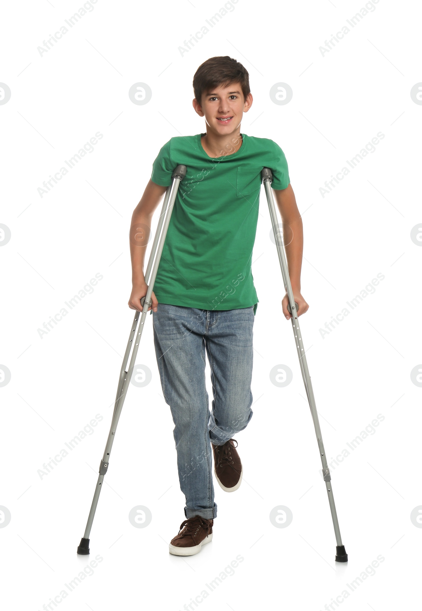 Photo of Teenage boy with injured leg using crutches on white background