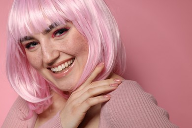 Happy woman with bright makeup and fake freckles on pink background, closeup