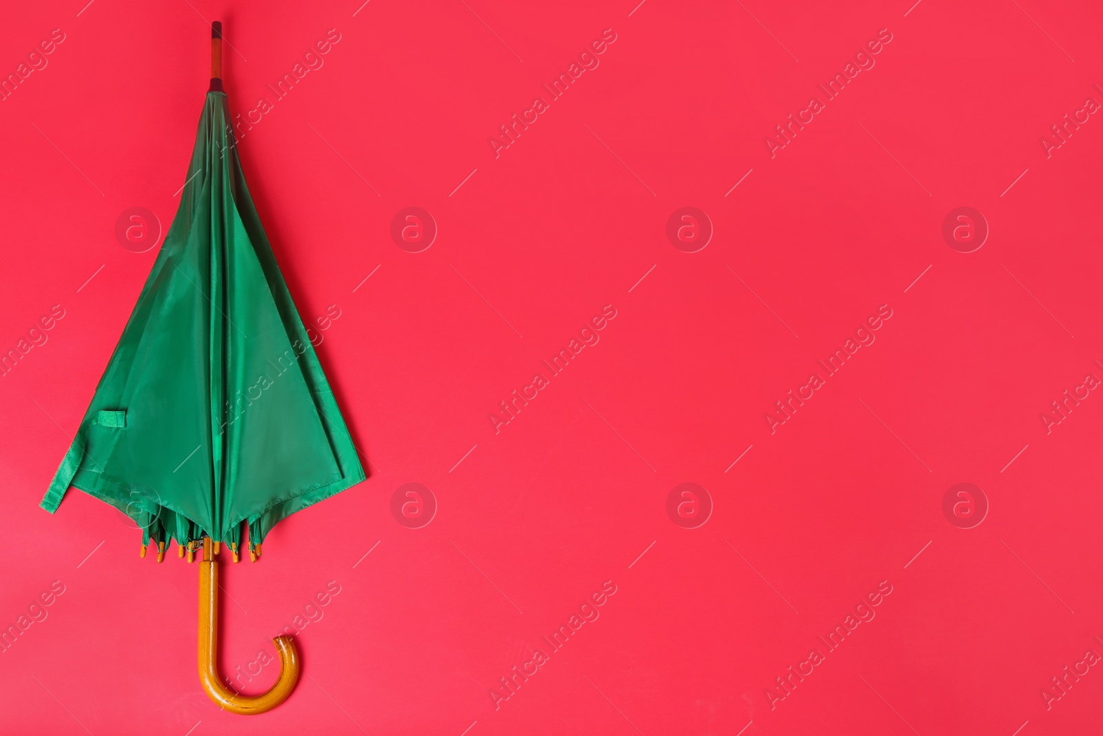 Photo of Beautiful green umbrella on red background, top view. Space for text