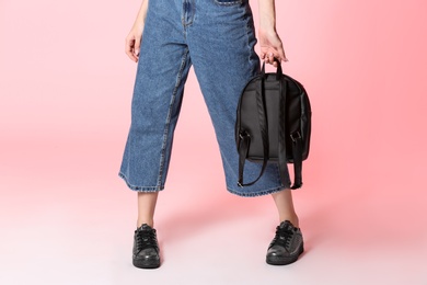 Photo of Fashionable woman in stylish shoes with backpack on color background