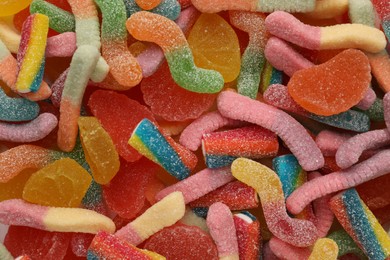 Many different tasty jelly candies as background, top view