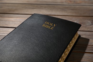 Old hardcover Bible on wooden table, closeup. Religious book