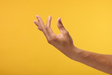 Photo of Man holding something in hand on orange background, closeup