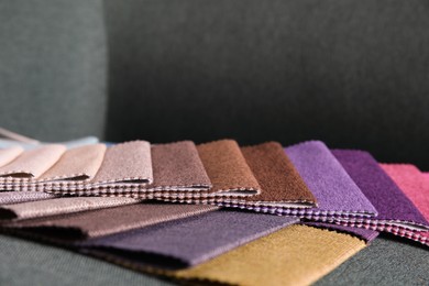 Photo of Catalog of colorful fabric samples on green background, closeup