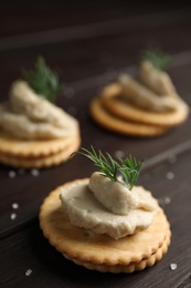 Photo of Delicious crackers with humus and dill on wooden table, closeup