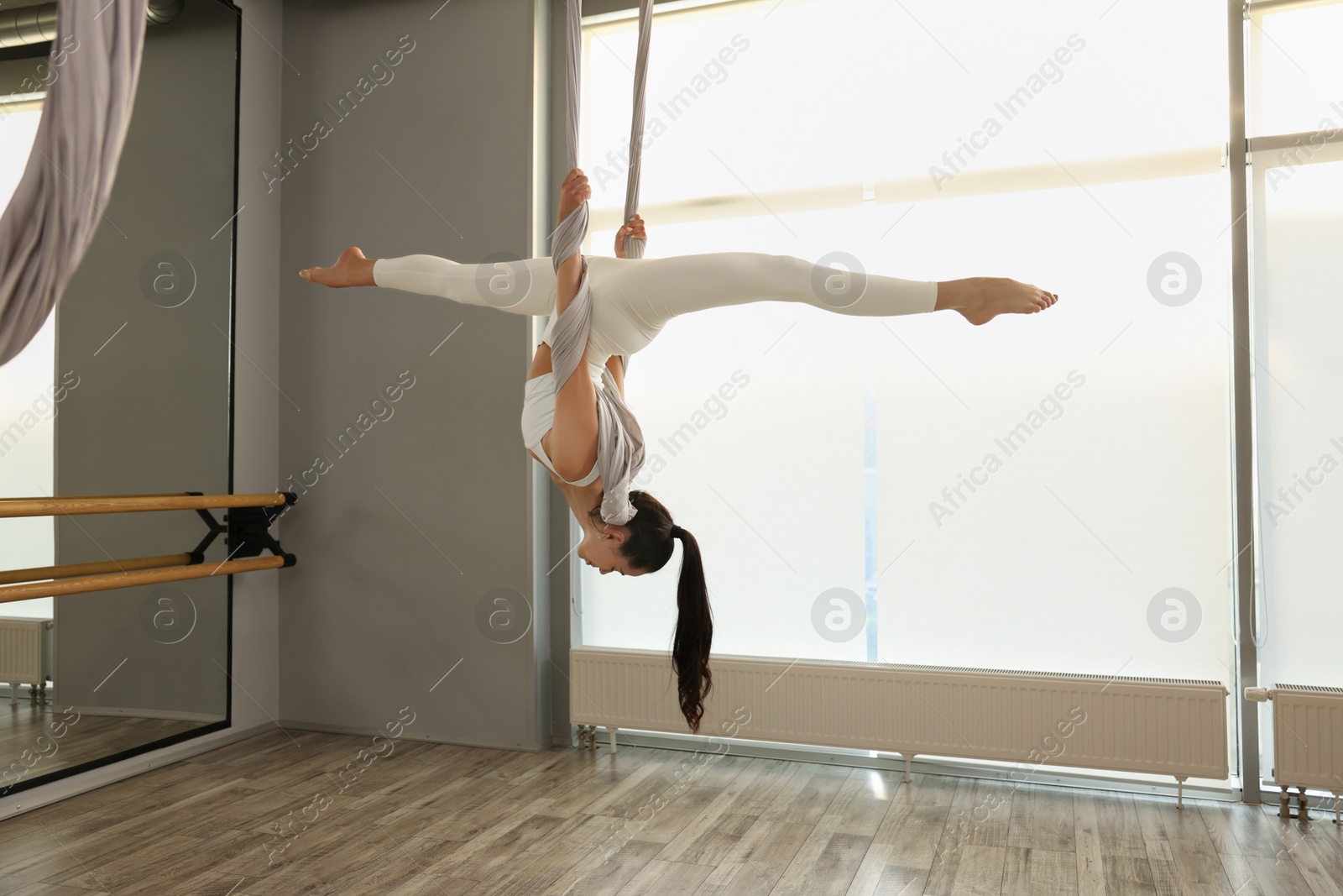 Photo of Young woman practicing fly yoga on hammock in studio