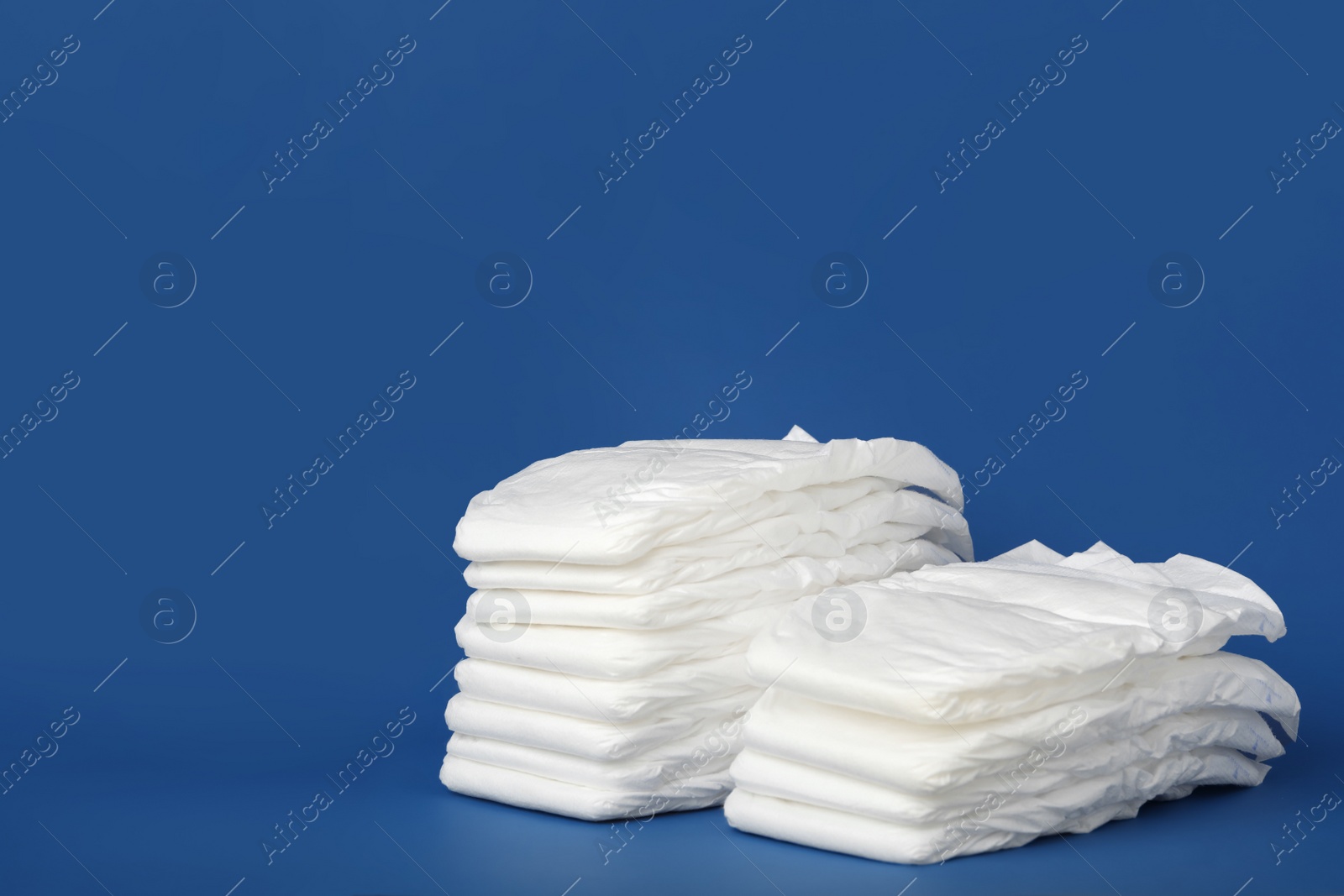 Photo of Stack of diapers on blue background. Space for text