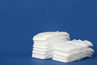 Stack of diapers on blue background. Space for text
