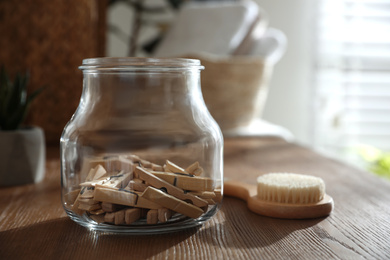 Photo of Jar with clothespins and shower brush on shelf indoors. Bathroom interior elements