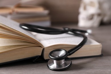 Photo of Open student textbook and stethoscope on wooden table, closeup. Medical education