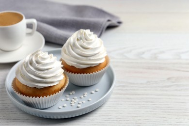 Photo of Delicious cupcakes with cream and cup of coffee on white wooden table. Space for text