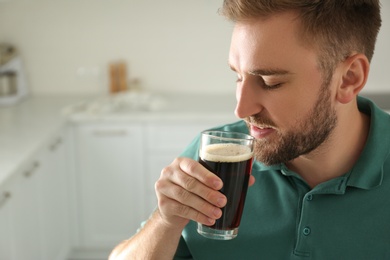 Photo of Handsome man with cold kvass indoors. Traditional Russian summer drink