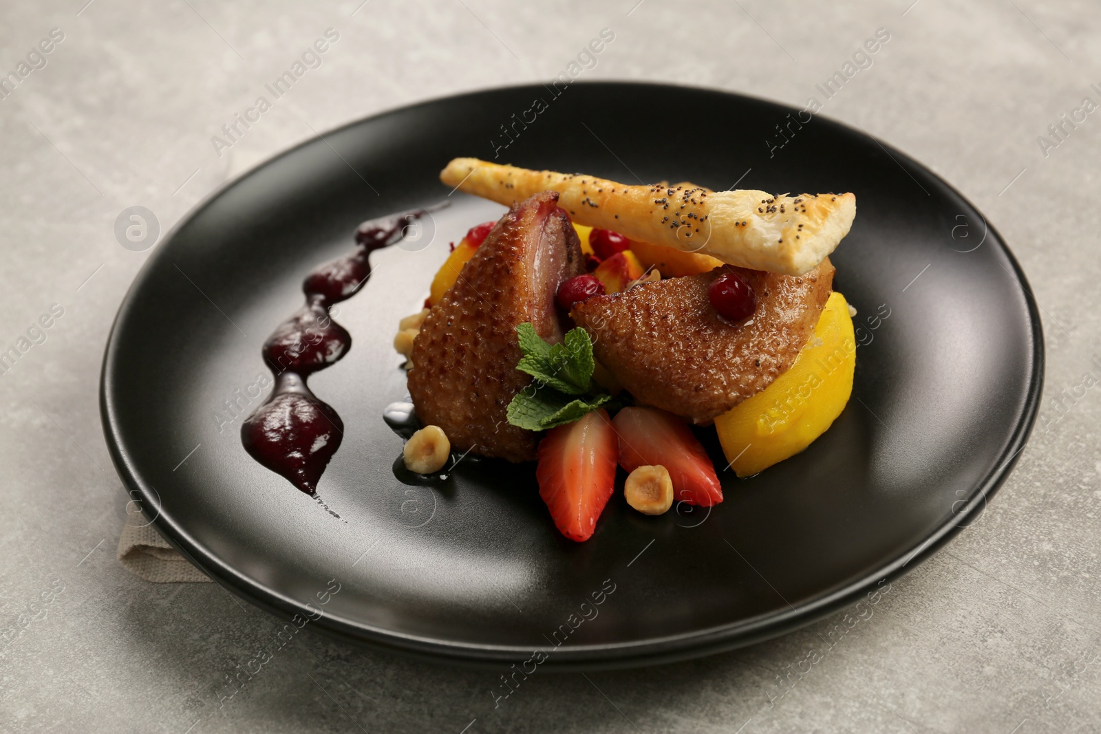 Photo of Plate with delicious chicken, parsnip and strawberries on grey table. Food stylist