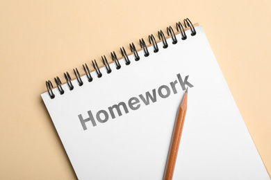 Image of Notebook with inscription HOMEWORK and pencil on beige background, top view