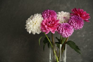 Photo of Bouquet of beautiful Dahlia flowers near dark grey wall, closeup