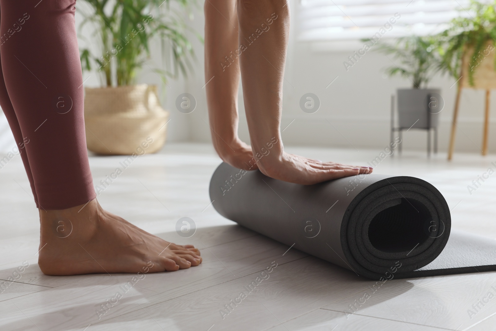 Photo of Woman unrolling yoga mat at home, closeup