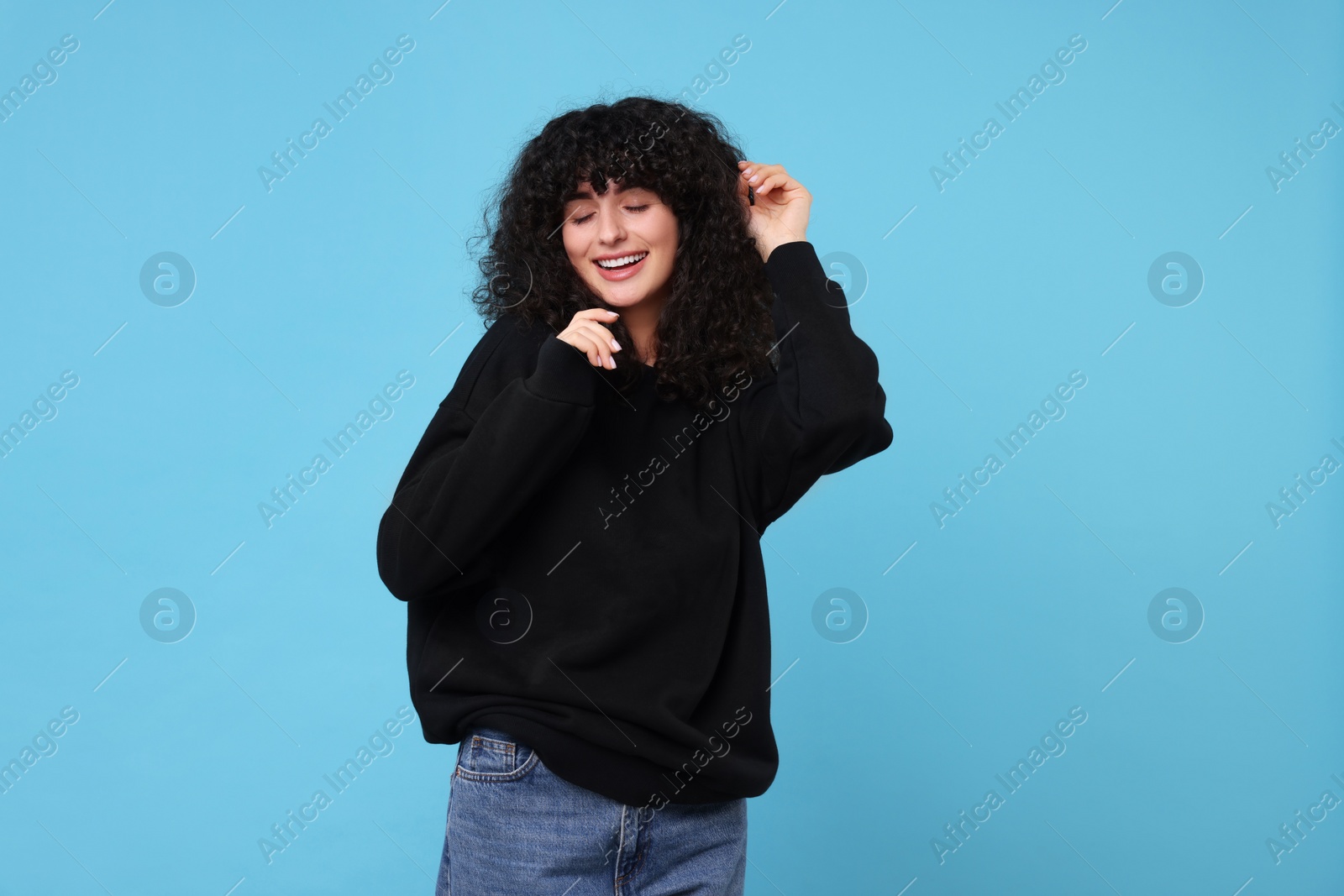 Photo of Happy young woman in stylish black sweater on light blue background