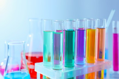 Different laboratory glassware with colorful liquids on grey background, closeup