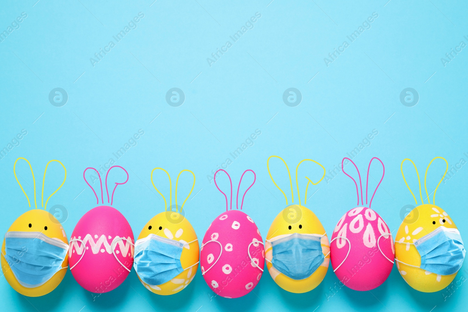 Image of COVID-19 pandemic. Colorful Easter eggs with cute bunny ears in protective masks and space for text on light blue background, flat lay